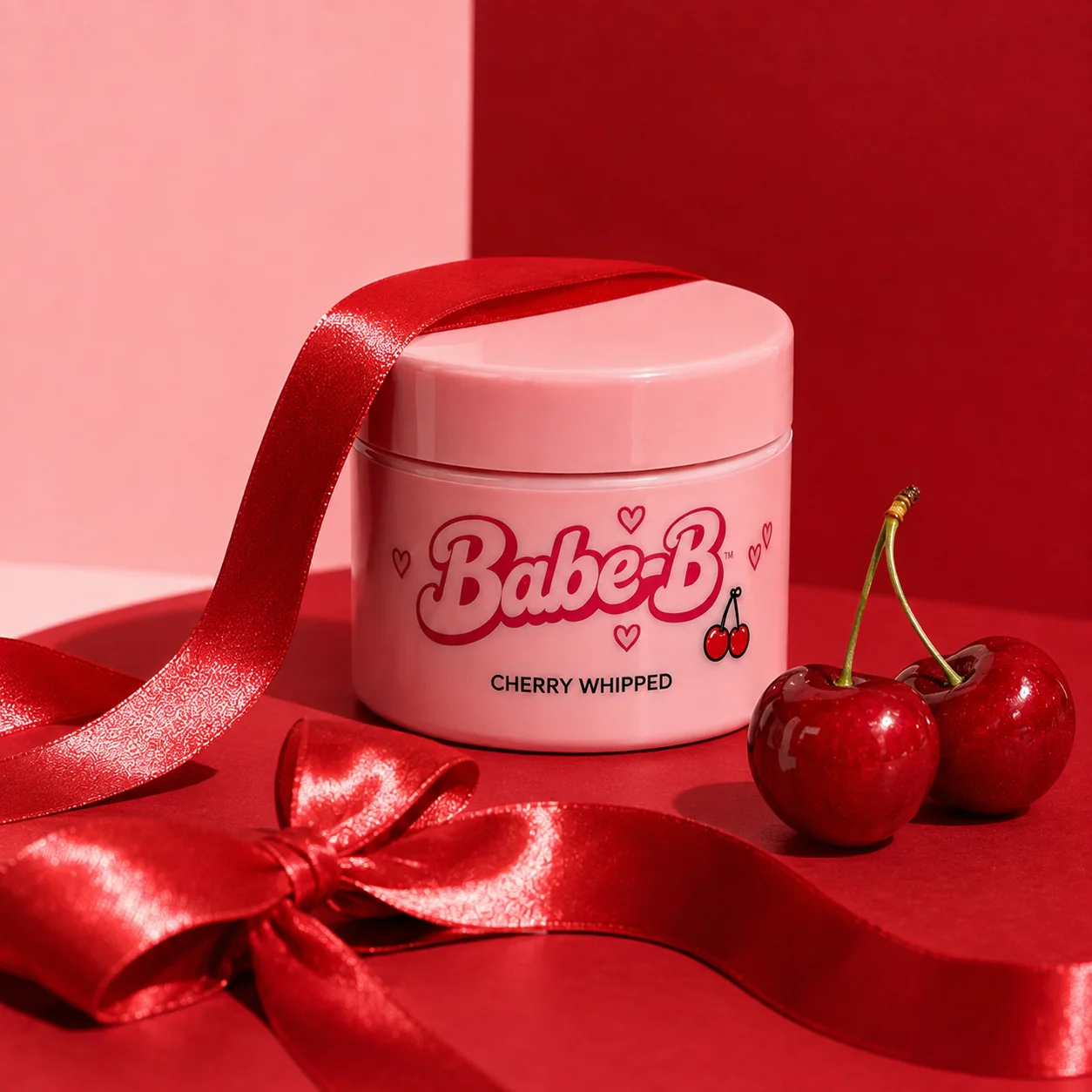 Babe-B pink jar concept with cherry-red satin ribbon and cherries on a pink and red background