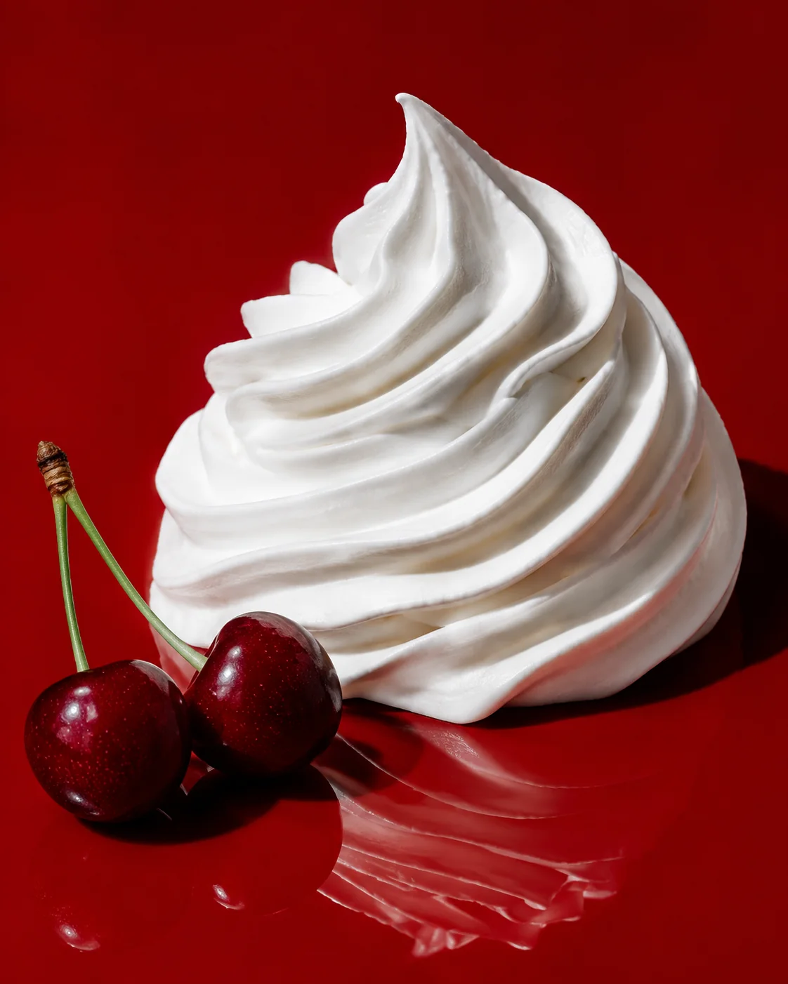 White whipped texture study with cherries placed separately on a red surface