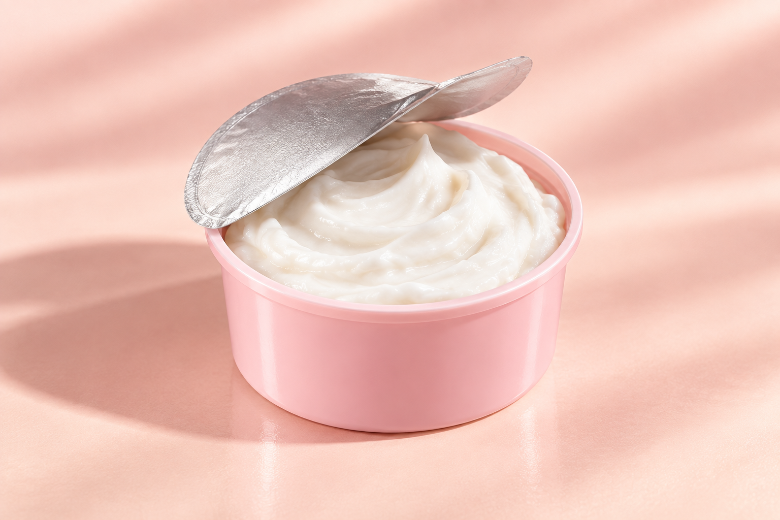 Pink refill cup concept with a partly peeled plain silver seal and white whipped cream